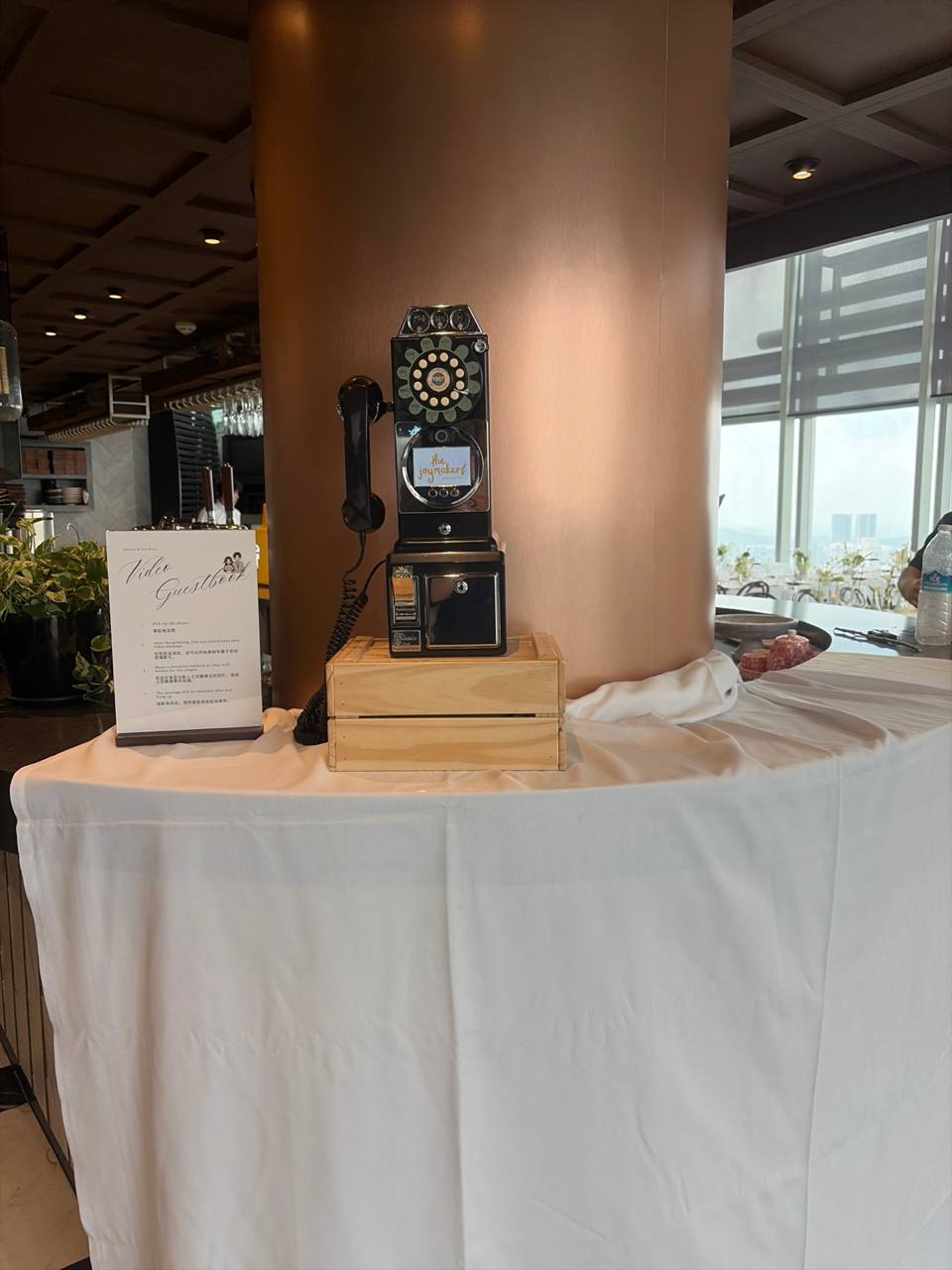 A black 1957-style payphone video guestbook on a wooden crate
