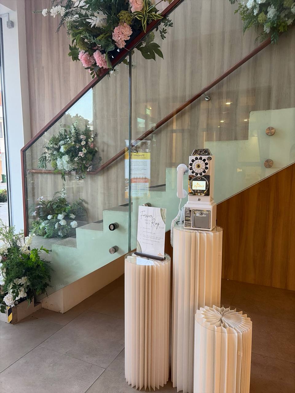 A white 1957-style payphone video guestbook beside a wedding flower arrangement